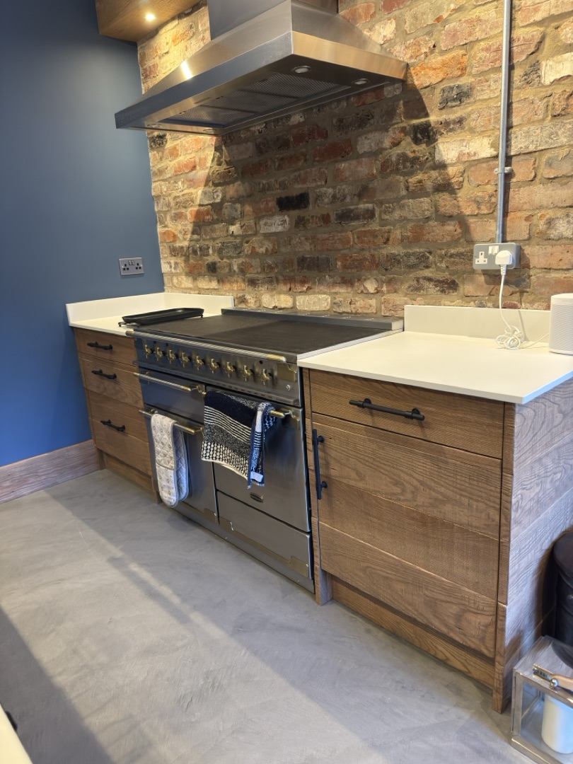 Watermill Lodge — range cooker set against exposed brick with oak cabinetry