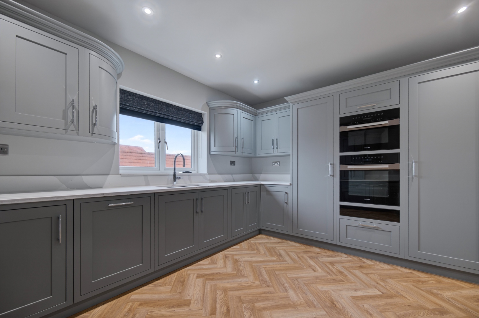 Grey in-frame kitchen showing curved corner unit and appliance tower — bespoke kitchen design