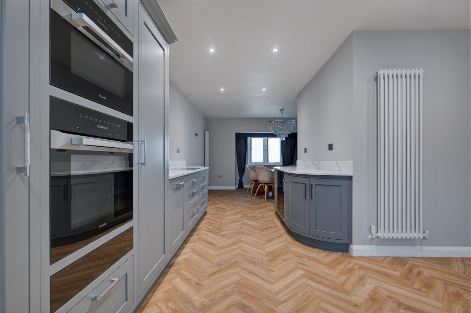 Integrated Miele appliances in bespoke kitchen — view through to curved island