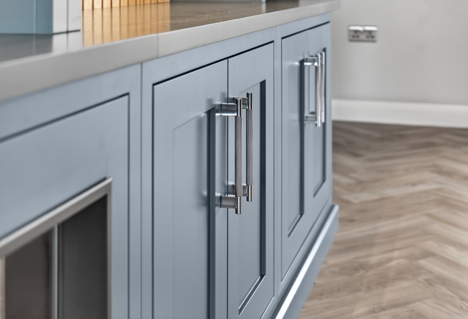 Chrome bar handles on grey in-frame shaker doors — kitchen hardware detail