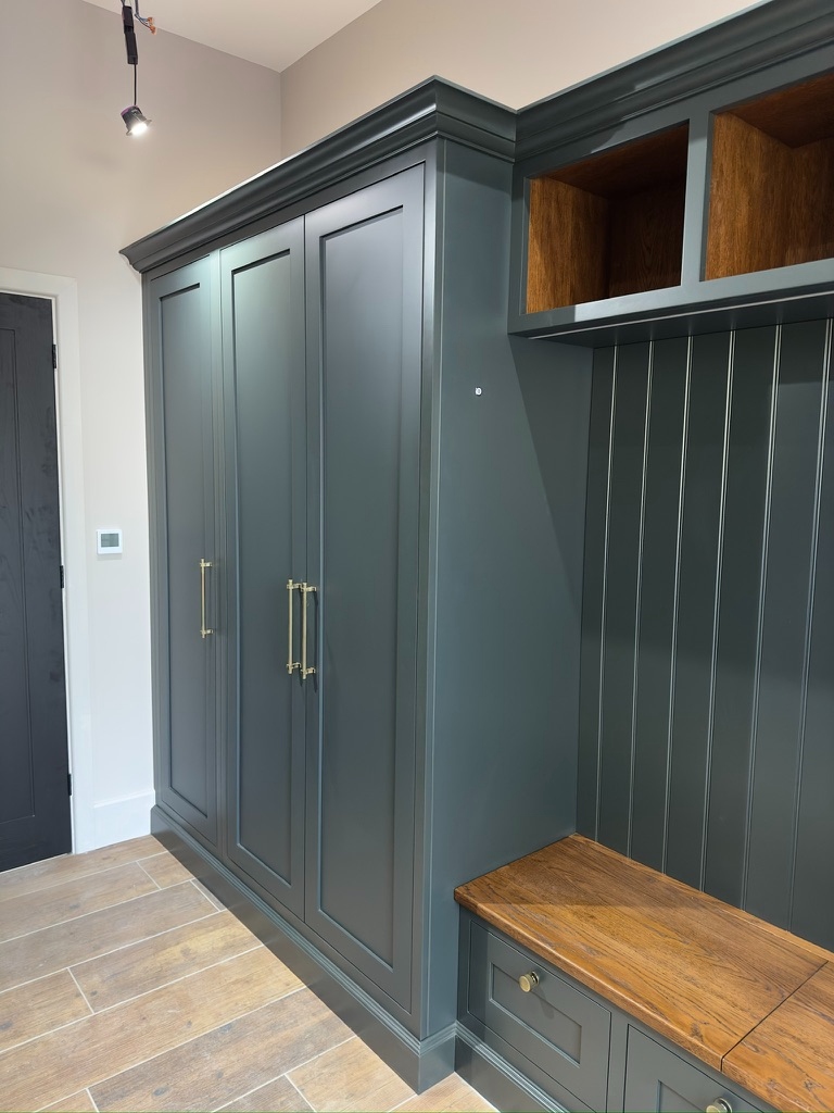 The Stables — green boot room full view with wardrobes, oak cubbies, and brass hardware