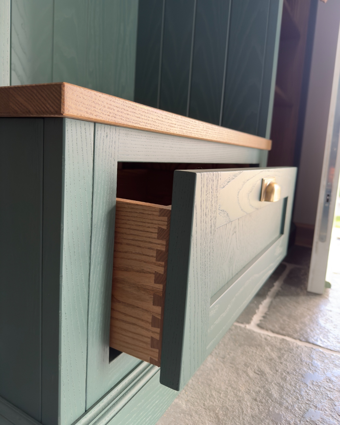 Dovetailed oak drawer with brass knob — traditional joinery in teal painted cabinetry