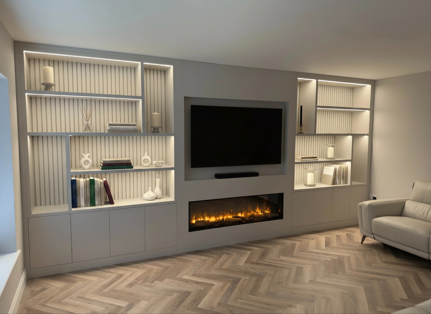 Bespoke cream media wall styled with books, candles, vases and dried flowers — LED-lit shelving, electric fireplace and herringbone flooring