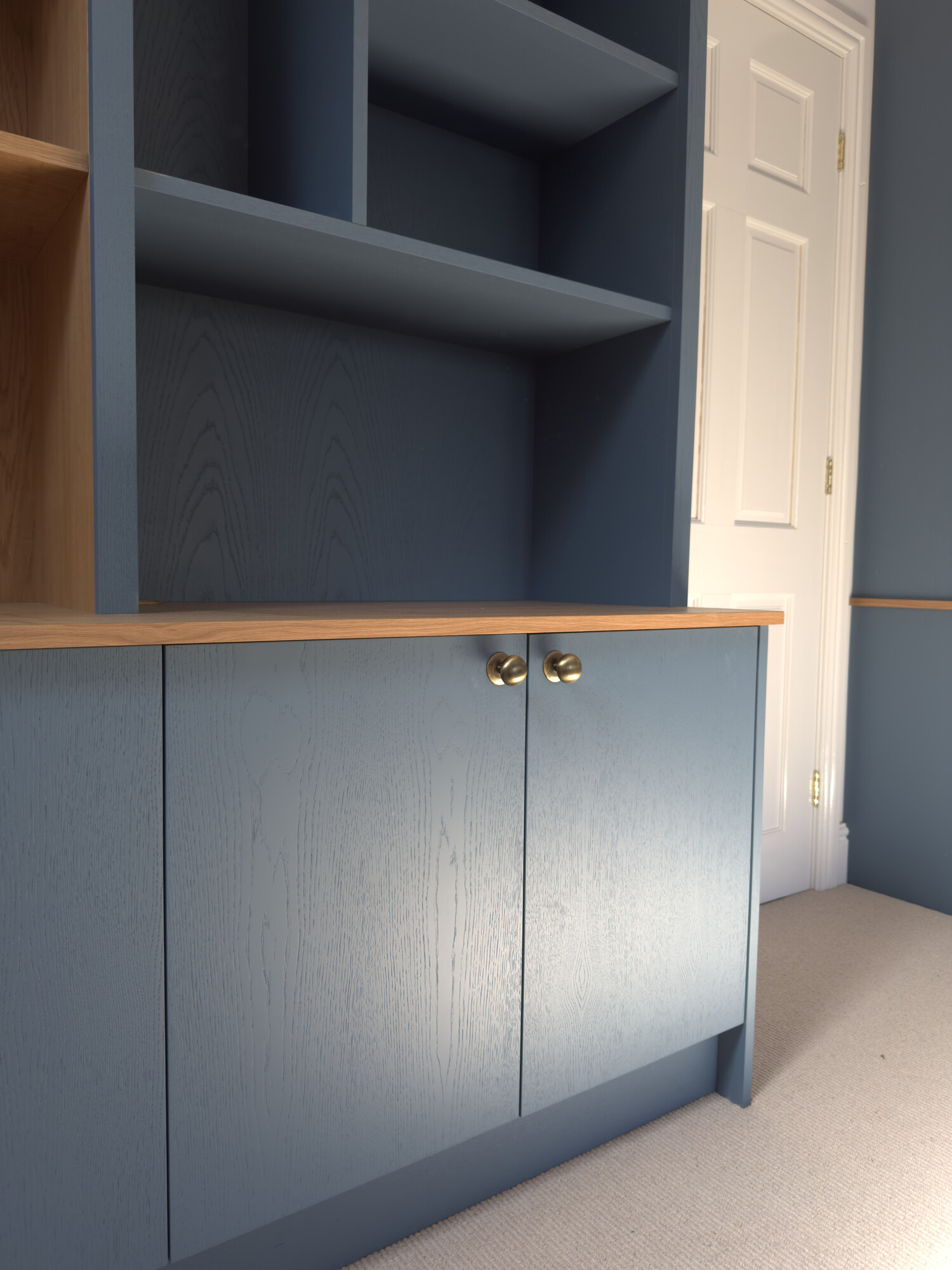 Blue painted cabinetry with brass knobs and oak top — bespoke shelving and storage detail