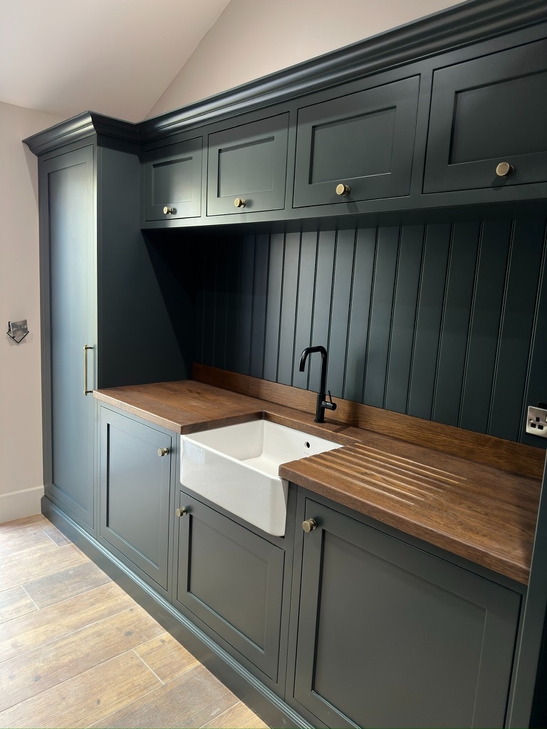 The Stables — green utility room with Belfast sink, upper cabinets, and oak worktop