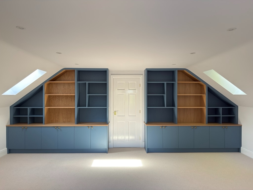 Watermill Lodge — blue under-eaves home office with symmetrical oak-lined shelving and storage